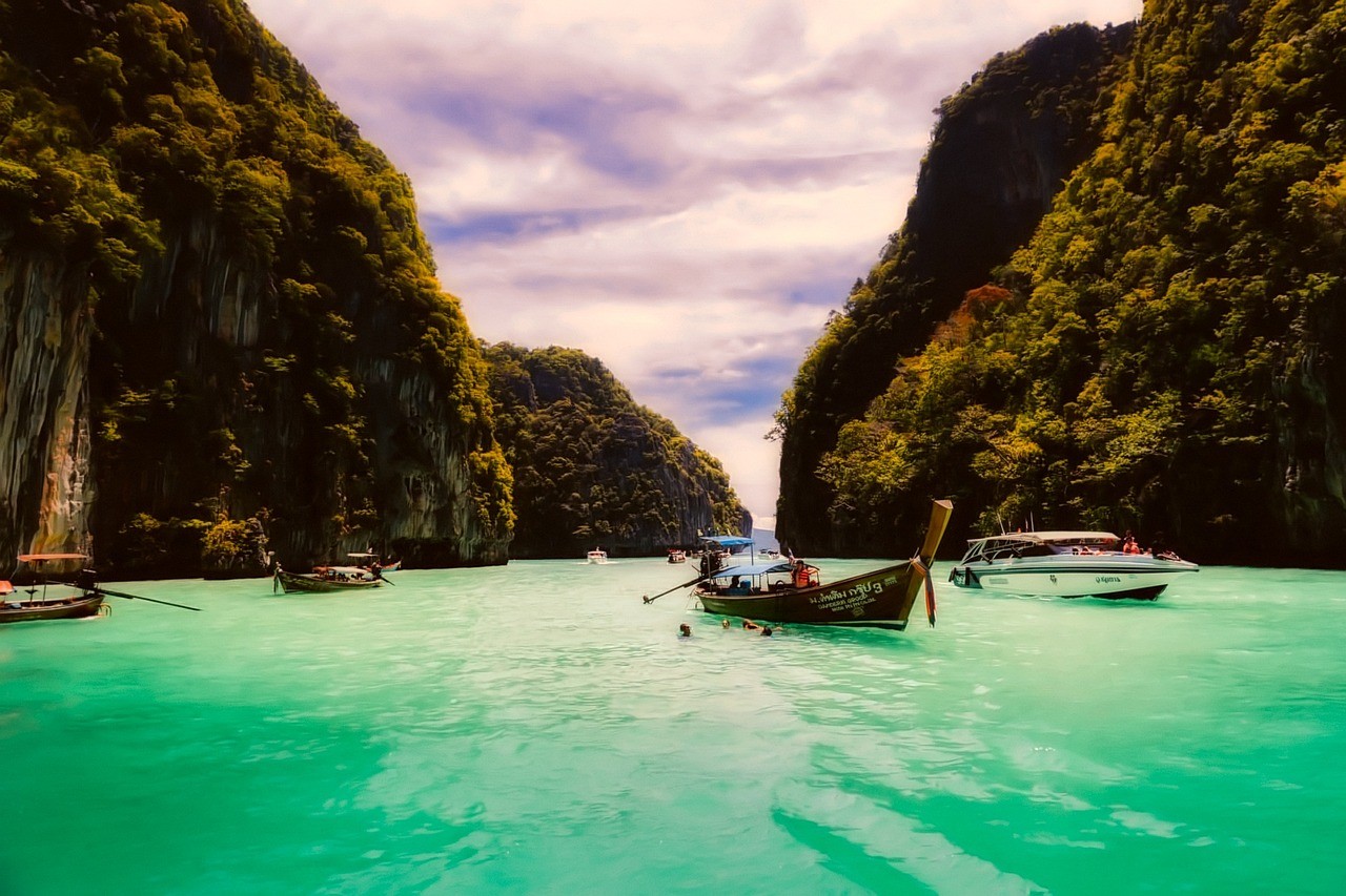 Small-group trip in Thailand: longtail boats in a turquoise lagoon framed by jungle cliffs